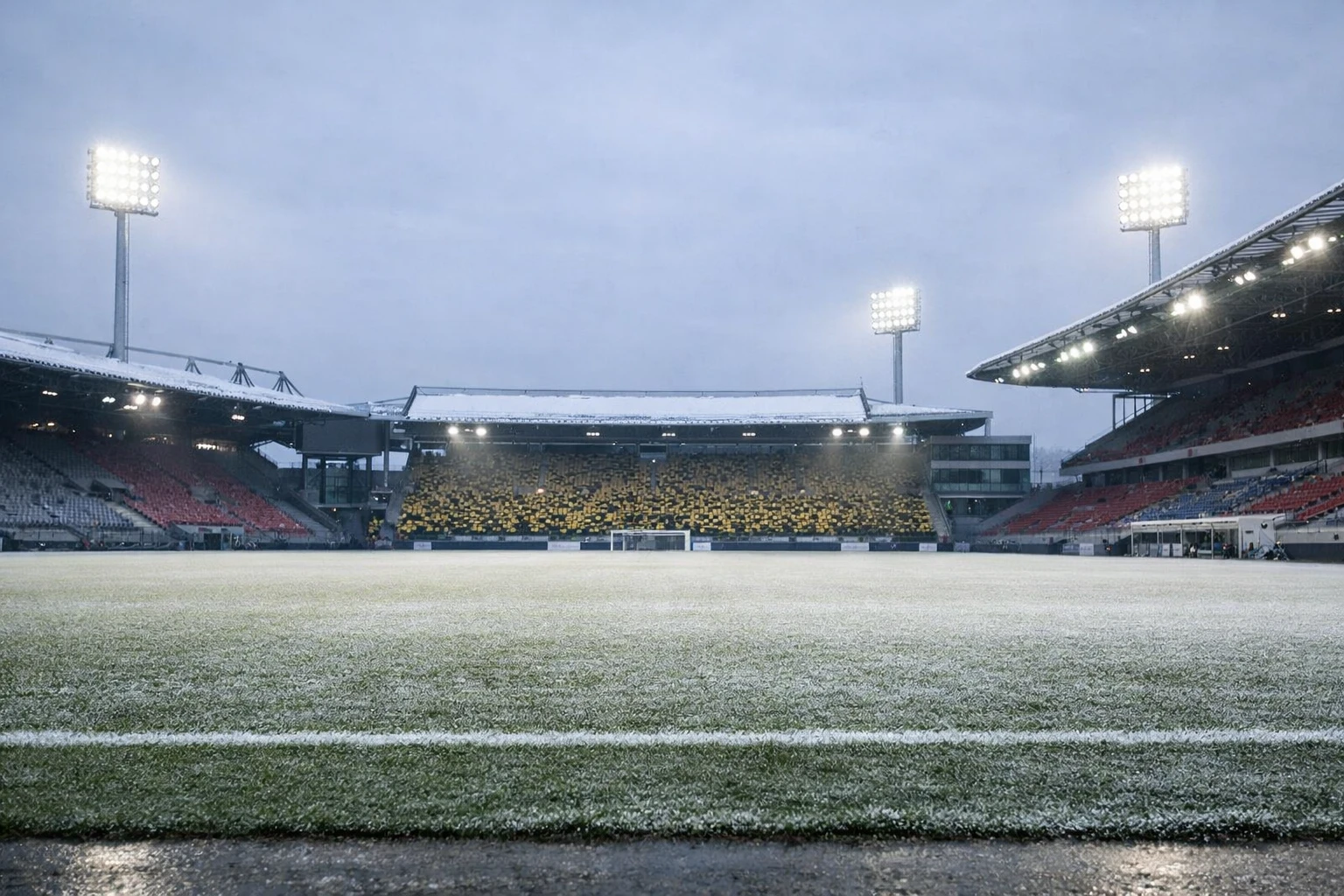 Bundesliga stadium during winter with snow on roof and frost-covered pitch